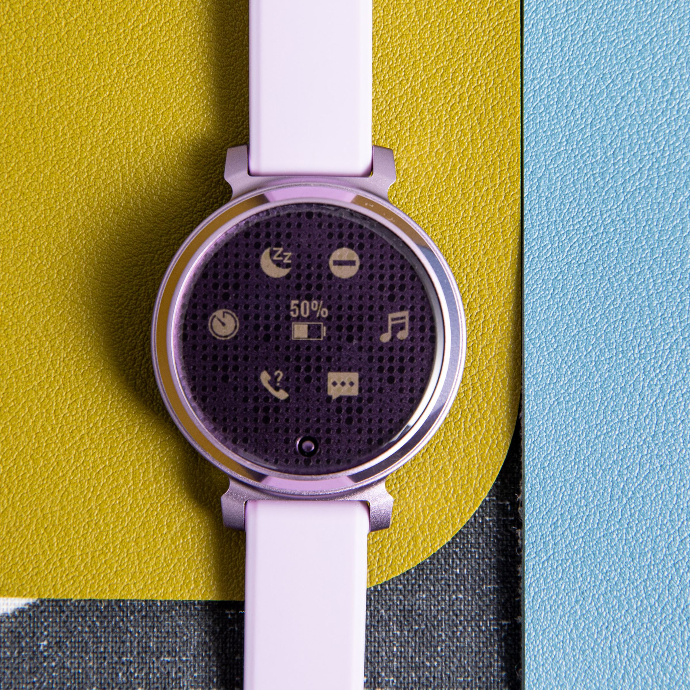 Gambar close-up Garmin Lily 2 warna ungu yang menyala pada latar belakang penuh warna.