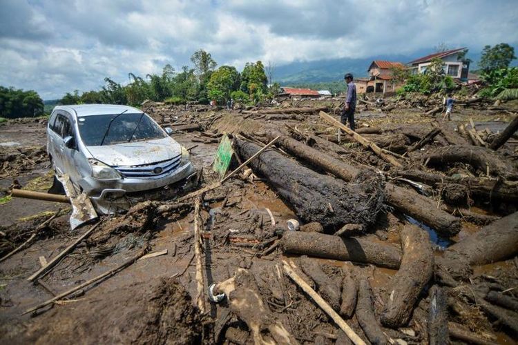 Warga melihat sebuah mobil yang terdampak banjir bandang di Nagari Bukik Batabuah, Agam, Sumatera Barat, Minggu (12/5/2024).