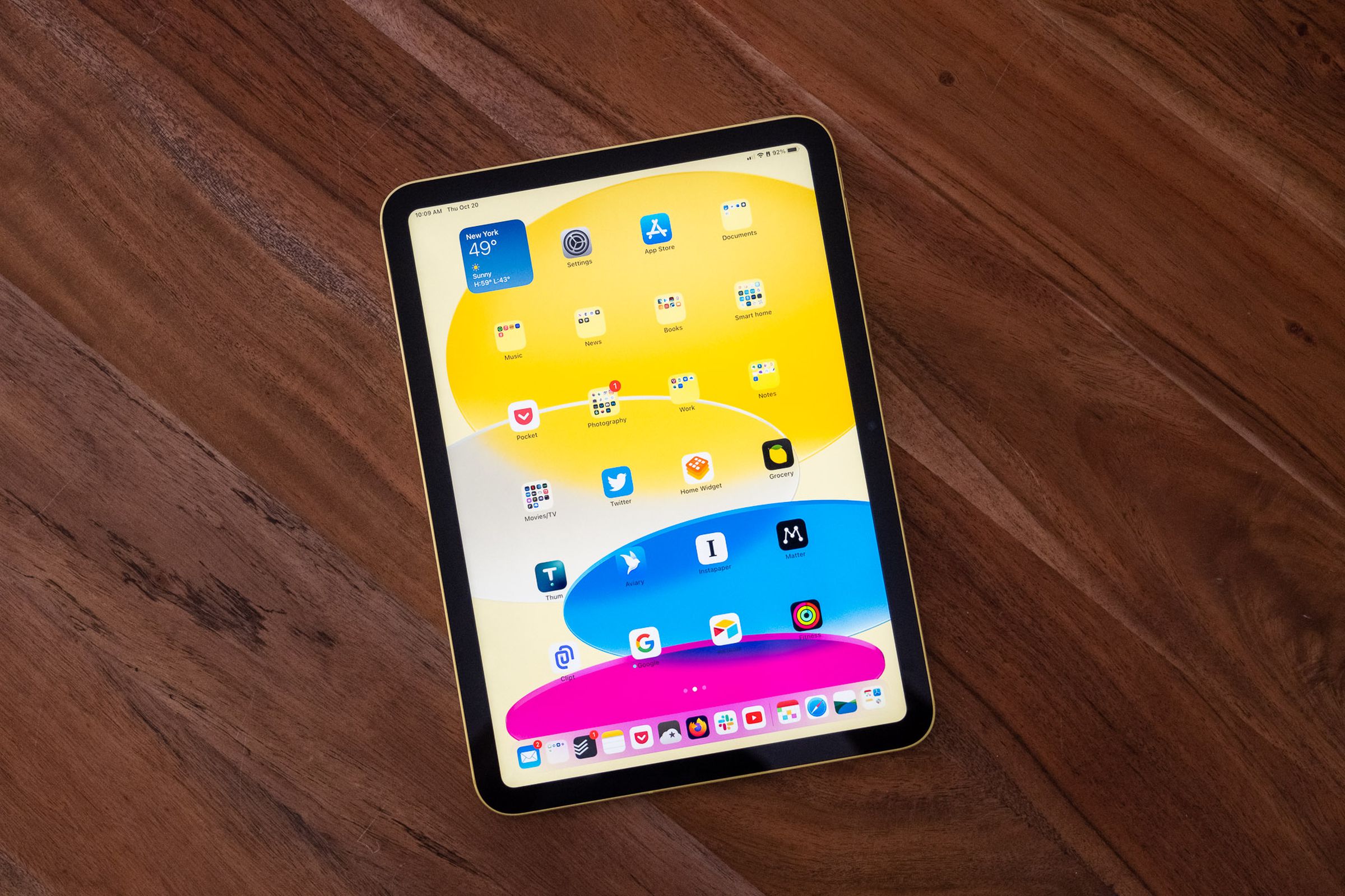 iPad Generasi 10 warna kuning, diletakkan di atas meja kayu.